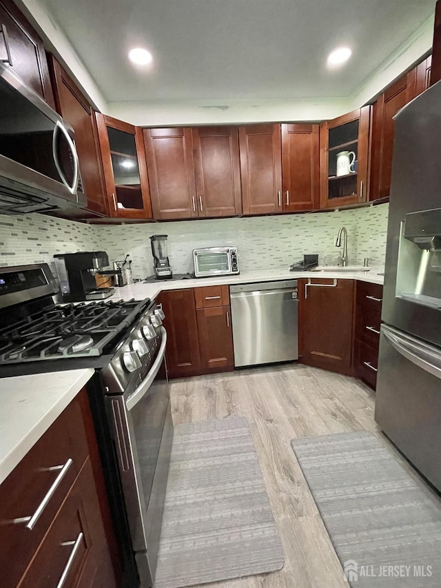 23 Hanover Sq Unit 23D, Middlesex, NJ 08846 - kitchen featuring stainless steel appliances, light countertops, light wood-style flooring, backsplash, and glass insert cabinets