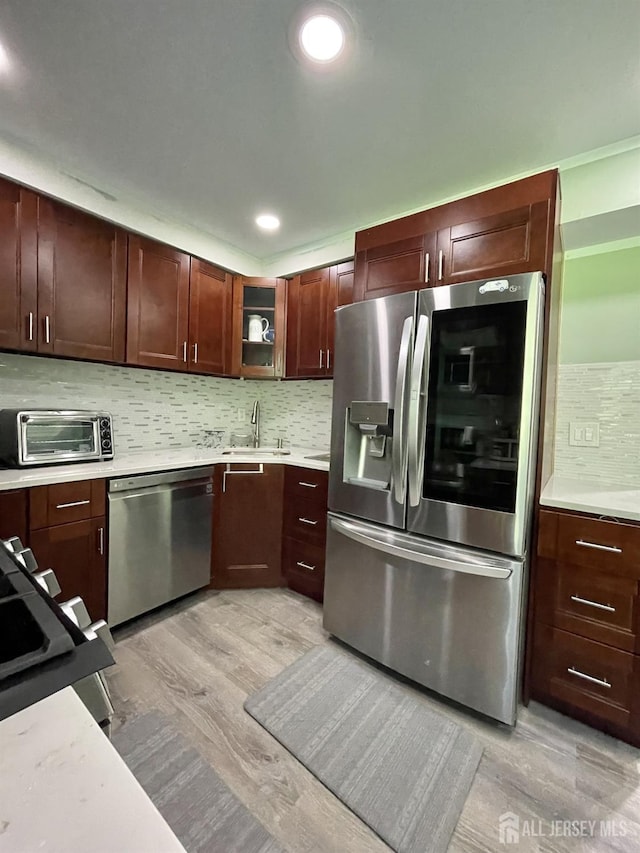 23 Hanover Sq Unit 23D, Middlesex, NJ 08846 - kitchen featuring appliances with stainless steel finishes, light wood-style flooring, light countertops, backsplash, and glass insert cabinets