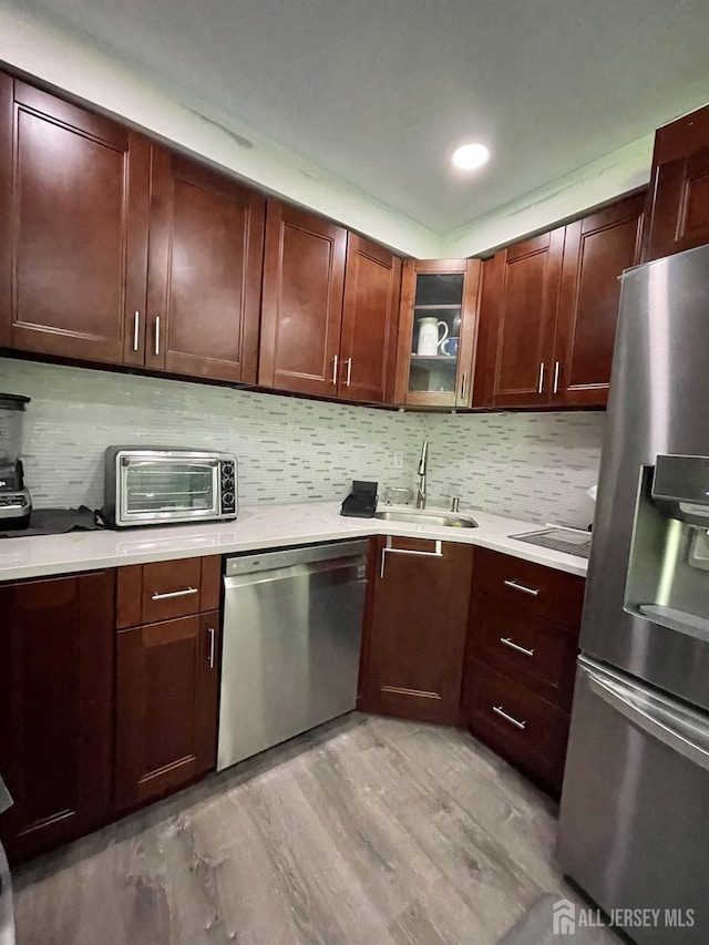 23 Hanover Sq Unit 23D, Middlesex, NJ 08846 - kitchen featuring stainless steel appliances, light wood finished floors, light countertops, decorative backsplash, and glass insert cabinets