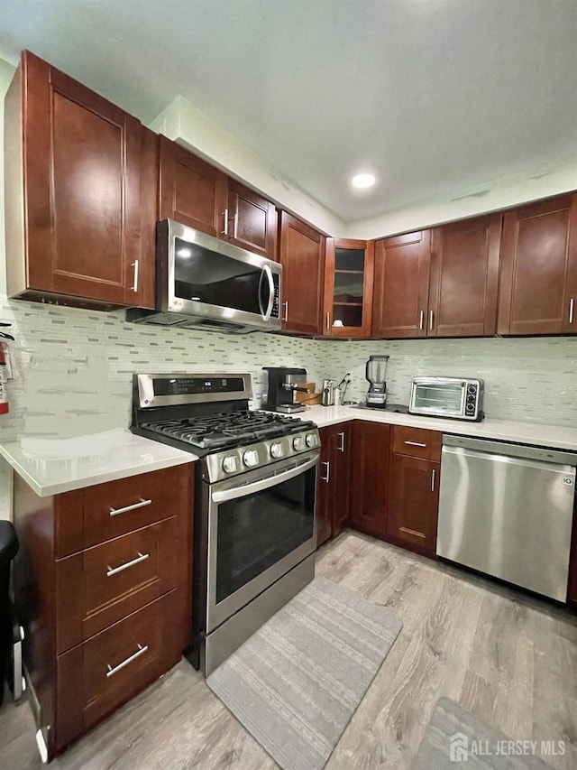 23 Hanover Sq Unit 23D, Middlesex, NJ 08846 - kitchen with stainless steel appliances, light wood-style flooring, light countertops, decorative backsplash, and glass insert cabinets