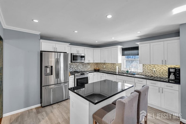 kitchen featuring light wood-style flooring, a sink, white cabinets, appliances with stainless steel finishes, and tasteful backsplash