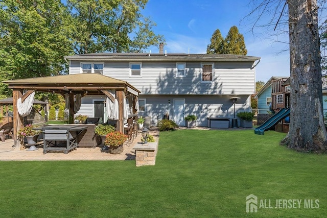 rear view of property featuring a gazebo, a patio, a lawn, and a playground