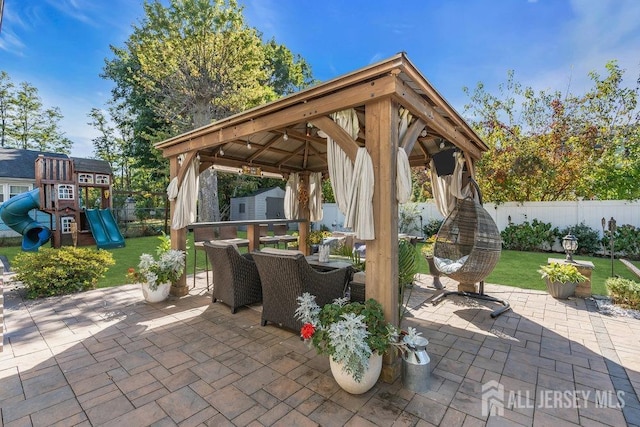 view of patio / terrace featuring a gazebo, outdoor dining space, a playground, and a fenced backyard