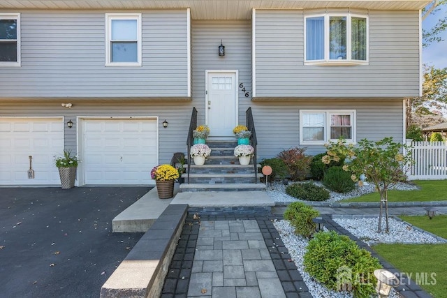 split foyer home featuring an attached garage, driveway, and fence