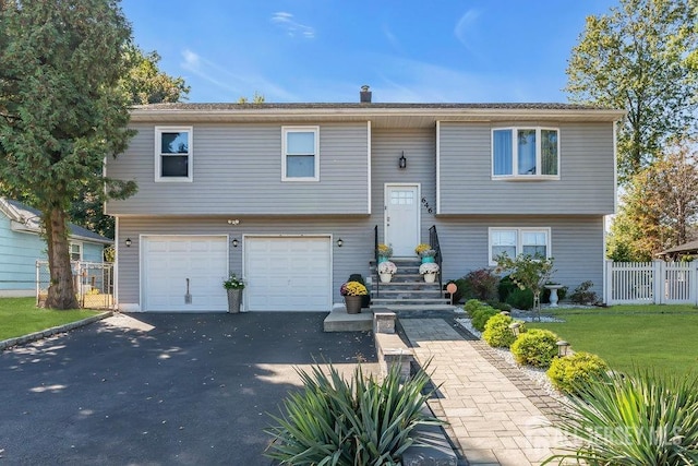 split foyer home with a front yard, fence, a garage, and driveway