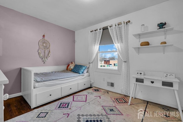 bedroom with visible vents, baseboards, and wood finished floors