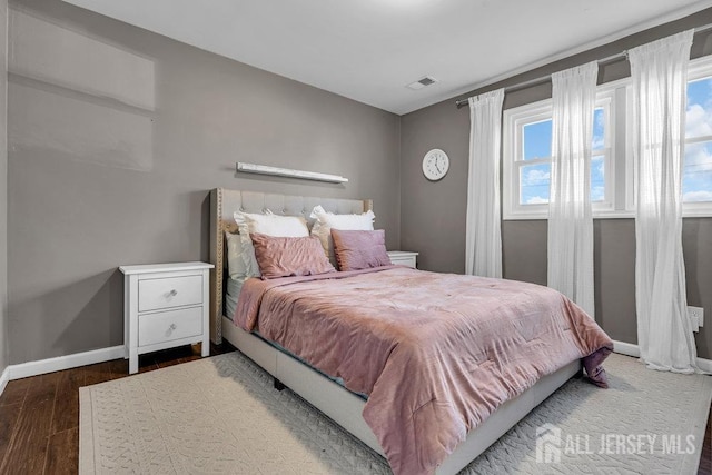 bedroom featuring visible vents, baseboards, and wood finished floors