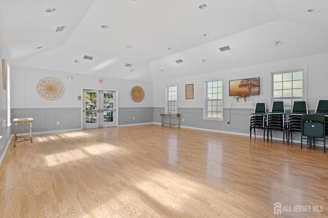 1905 Dahlia Cir S, Brunswick, NJ 08810 - living room featuring lofted ceiling, a decorative wall, light wood finished floors, french doors, and wainscoting