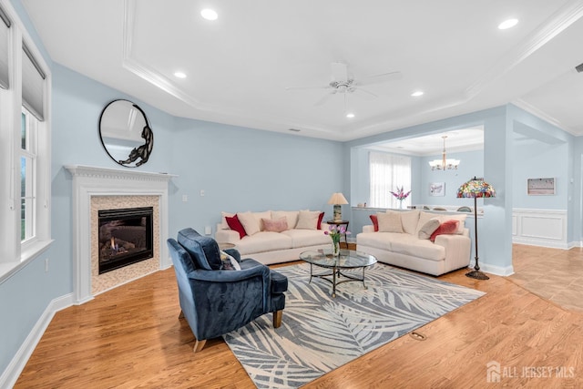 10 E Black Heath Ct, Howell, NJ 07727 - living room featuring ornamental molding, a tray ceiling, ceiling fan, light wood-style floors, and a glass covered fireplace