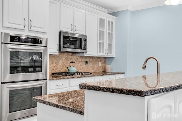 10 E Black Heath Ct, Howell, NJ 07727 - kitchen featuring appliances with stainless steel finishes, glass insert cabinets, tasteful backsplash, crown molding, and white cabinetry