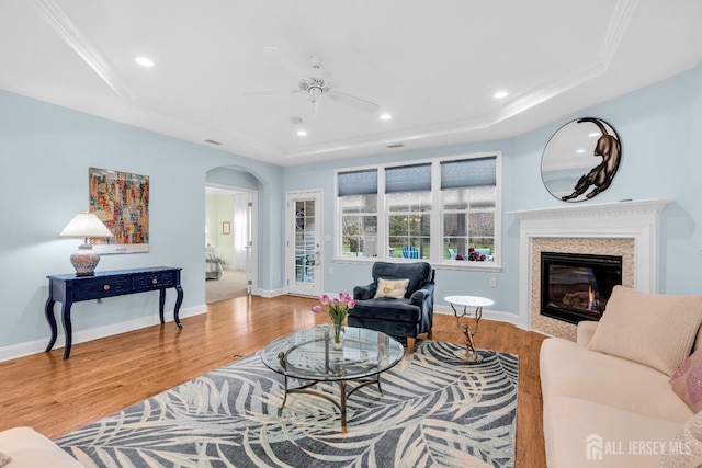 10 E Black Heath Ct, Howell, NJ 07727 - living room with a raised ceiling, arched walkways, wood finished floors, a ceiling fan, and a glass covered fireplace