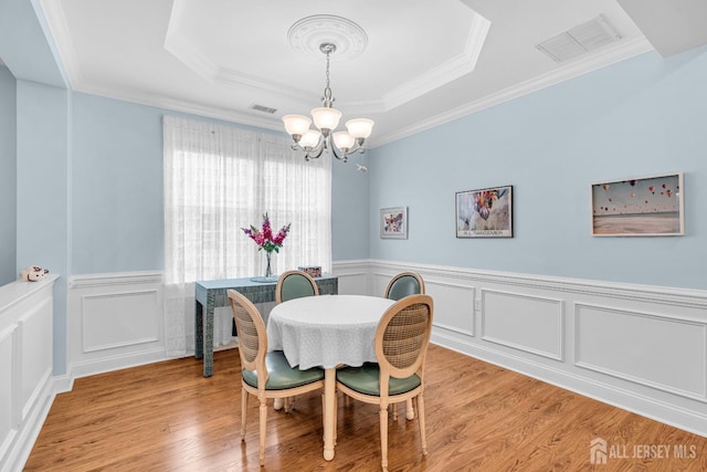 10 E Black Heath Ct, Howell, NJ 07727 - dining room with a tray ceiling, a chandelier, wood finished floors, a wainscoted wall, and a decorative wall