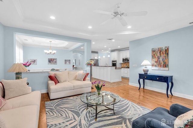 10 E Black Heath Ct, Howell, NJ 07727 - living area with a raised ceiling, crown molding, light wood-style flooring, a chandelier, and a ceiling fan