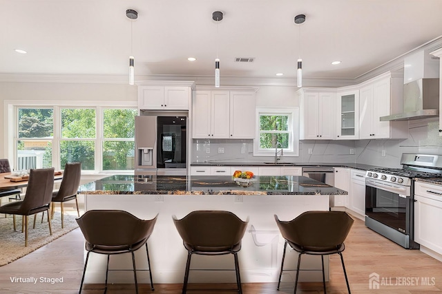 kitchen with pendant lighting, stainless steel range with gas stovetop, a center island, and fridge with ice dispenser