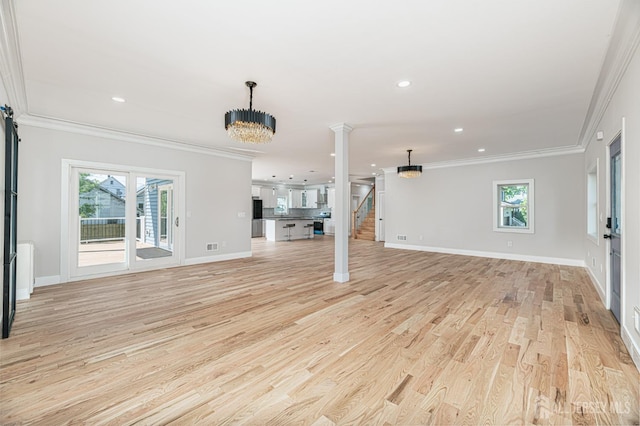 unfurnished living room featuring crown molding, a wealth of natural light, a chandelier, and light wood-type flooring