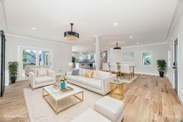 living room with crown molding, a chandelier, and light wood-type flooring