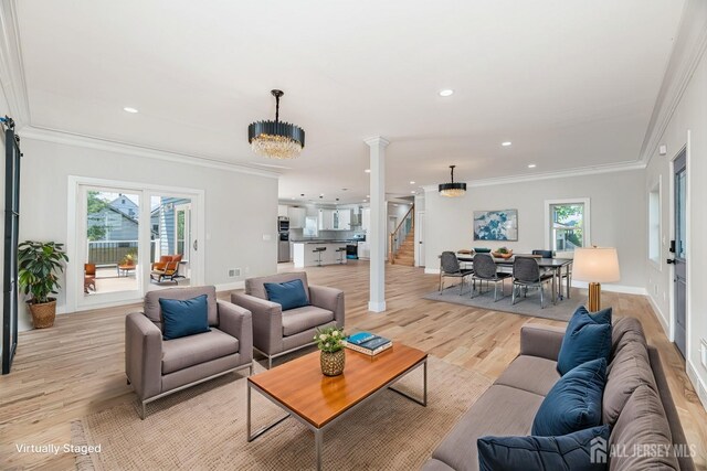 living room featuring crown molding, light hardwood / wood-style floors, decorative columns, and a notable chandelier