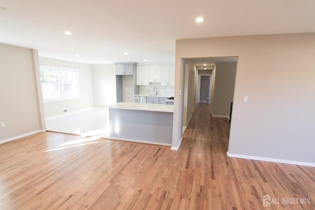 6 Joan St, South Brunswick, NJ 08824 - kitchen with a sink, decorative backsplash, light wood-type flooring, baseboards, and light countertops