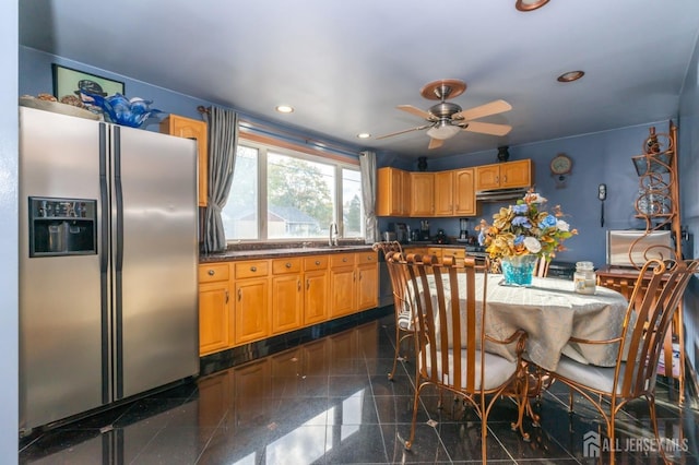 kitchen with stainless steel fridge, dark countertops, granite finish floor, a sink, and recessed lighting