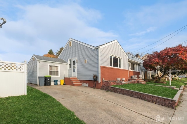 rear view of property with entry steps, brick siding, a lawn, and fence