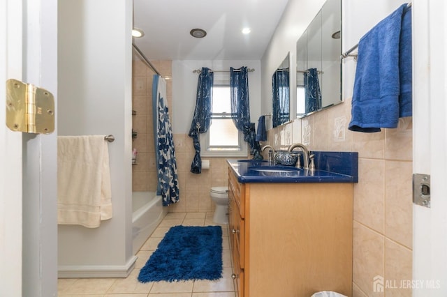 full bathroom with shower / tub combo with curtain, tile walls, toilet, vanity, and tile patterned floors