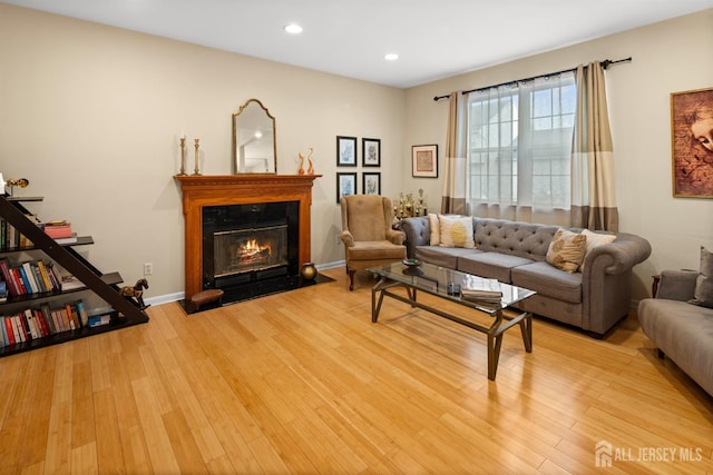 living room with a glass covered fireplace, recessed lighting, and light wood-style floors