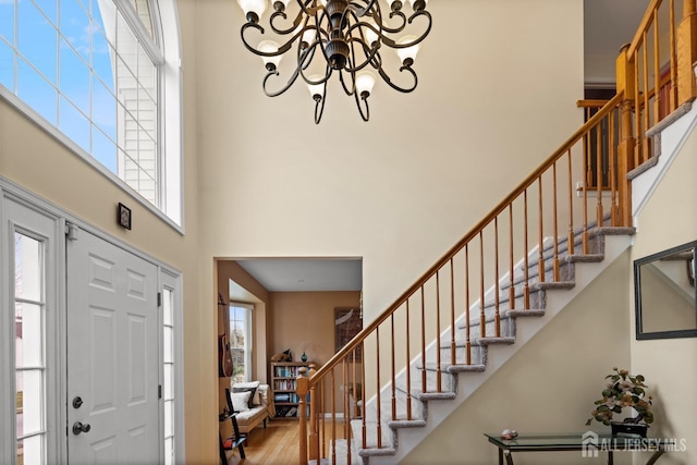 entryway with a notable chandelier, stairway, a towering ceiling, and a healthy amount of sunlight