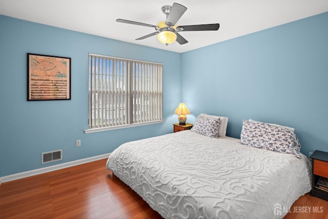 bedroom featuring baseboards, a ceiling fan, wood finished floors, and visible vents