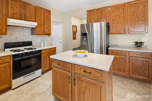 kitchen featuring stainless steel refrigerator with ice dispenser, white range with gas stovetop, under cabinet range hood, and brown cabinets