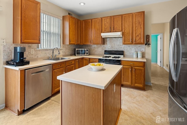 kitchen with under cabinet range hood, tasteful backsplash, stainless steel appliances, and a sink