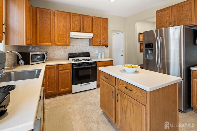 kitchen featuring tasteful backsplash, a sink, stainless steel appliances, light countertops, and under cabinet range hood