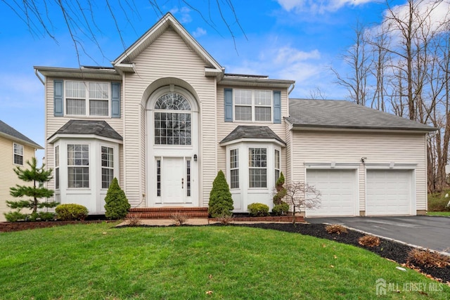 view of front facade featuring an attached garage, aphalt driveway, and a front yard
