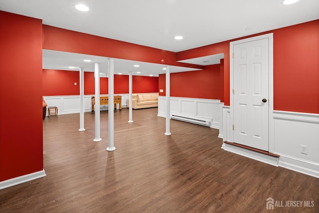 finished below grade area featuring a decorative wall, a baseboard radiator, a wainscoted wall, and wood finished floors