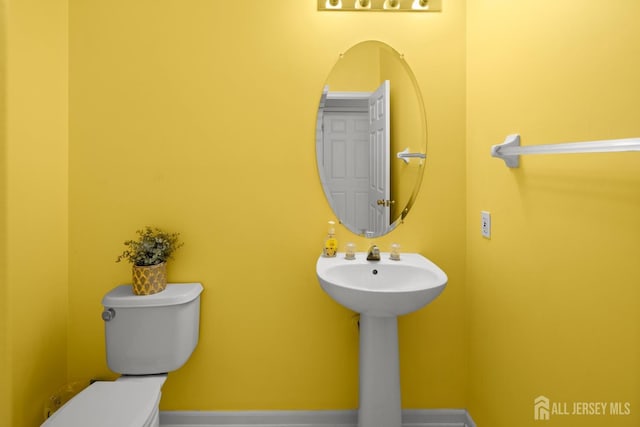 half bathroom featuring toilet and baseboards