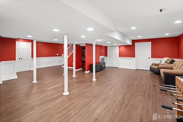 finished below grade area featuring a decorative wall, a wainscoted wall, recessed lighting, and wood finished floors