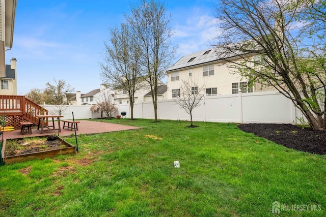 view of yard with a garden, a patio area, a fenced backyard, a wooden deck, and a residential view