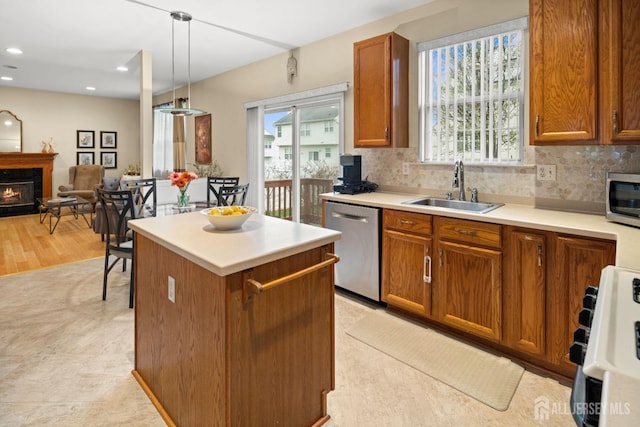 kitchen with brown cabinetry, a kitchen island, appliances with stainless steel finishes, and a sink