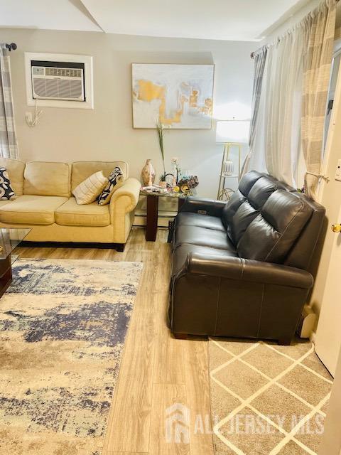 living area with an AC wall unit and wood finished floors