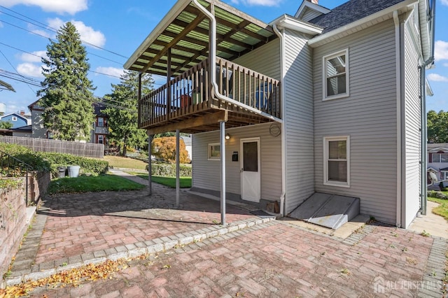 rear view of house with a patio area, fence, a deck, and roof with shingles