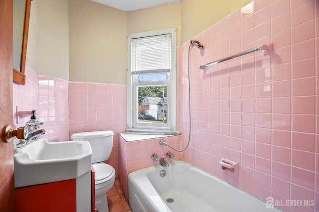 bathroom with toilet, a garden tub, vanity, and tile walls