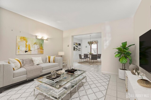 living area featuring light tile patterned floors, a chandelier, and baseboards