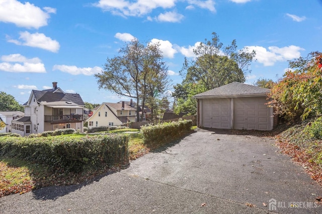 exterior space featuring an outbuilding, a detached garage, a residential view, and a balcony