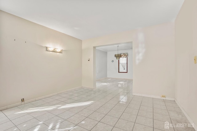 spare room featuring a notable chandelier, baseboards, and light tile patterned floors