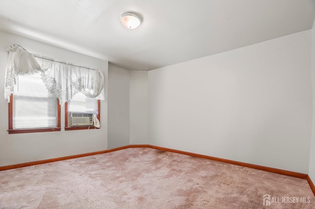 empty room featuring light colored carpet and baseboards