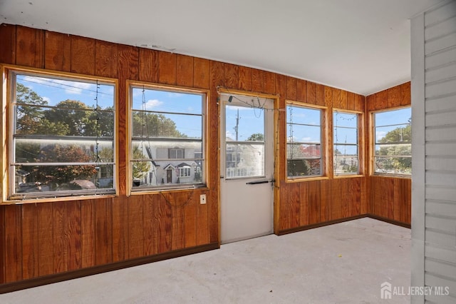 unfurnished sunroom with healthy amount of natural light and wooden walls