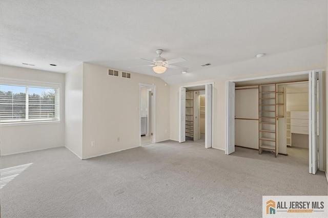 unfurnished bedroom featuring two closets, baseboards, visible vents, and carpet