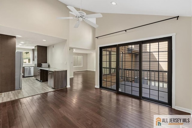 unfurnished living room with ceiling fan, wood finished floors, baseboards, high vaulted ceiling, and recessed lighting