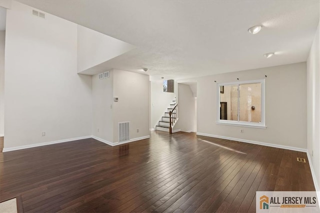 unfurnished living room with stairs, visible vents, and hardwood / wood-style floors