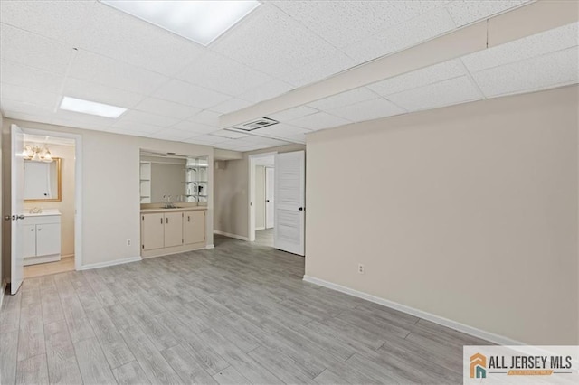 unfurnished living room with visible vents, light wood-style flooring, and a drop ceiling