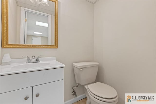 half bath featuring vanity, baseboards, and toilet